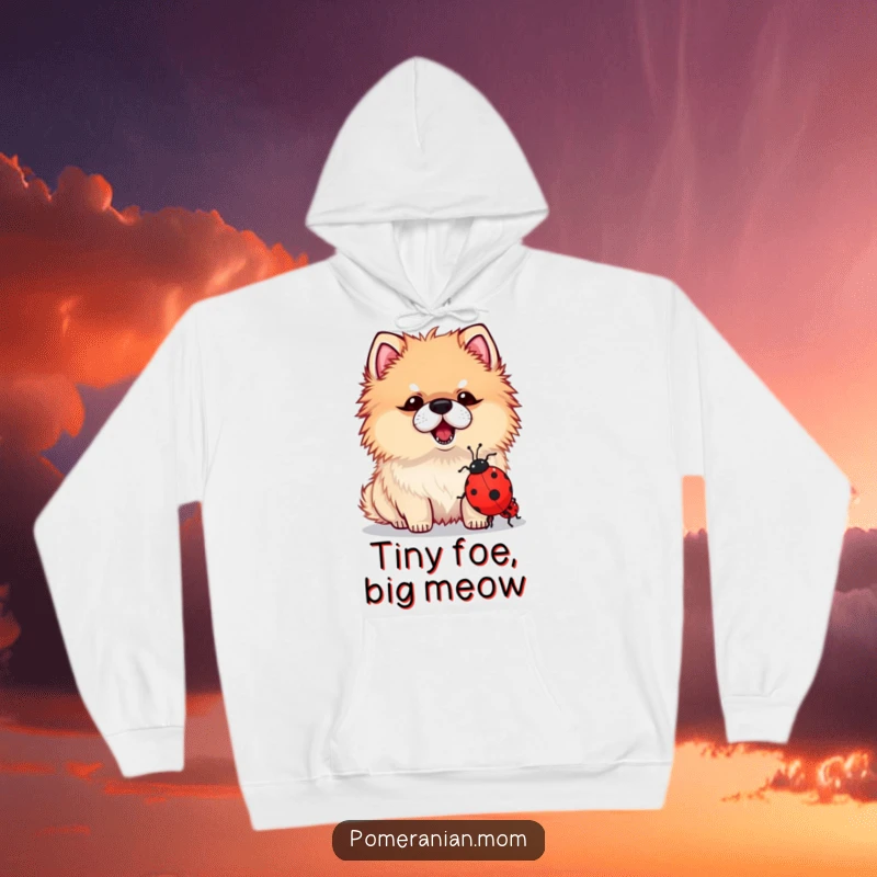 Funny hoodie displaying a kawaii Pomeranian barking with courage at a tiny ladybug, a humorous and heartwarming pet scene.